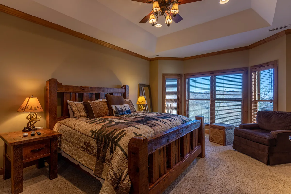 A king bedroom featuring a wooden bed frame with decorative bedding, large windows that allow in abundant natural light, side lamps for nighttime reading, and a comfortable armchair for relaxation. The space exudes warmth and comfort, ideal for unwinding after a day of adventure.