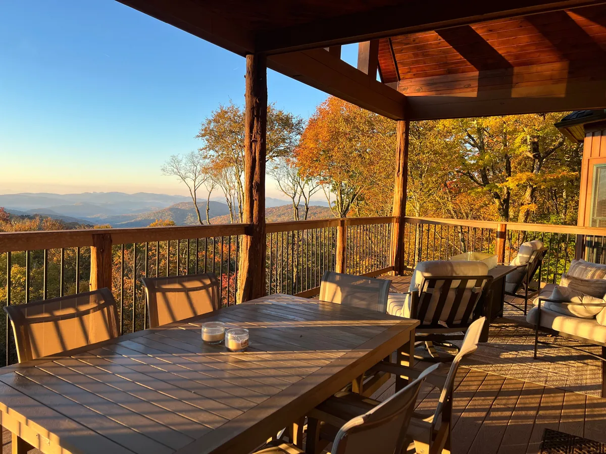 This image captures an outdoor dining table set on a deck with scenic mountain views and vibrant autumn foliage all around. The table is ready for al fresco meals, and the panoramic view underscores the section’s emphasis on dining and celebrating in nature’s embrace.