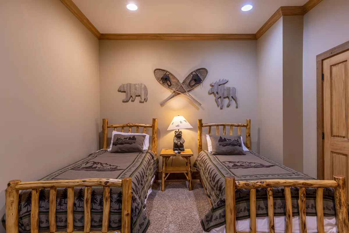 A twin bedroom with two rustic wooden beds, decorative animal-themed wall art, and a unique lamp, creating a playful yet restful environment perfect for children or grandparents seeking a quiet evening.