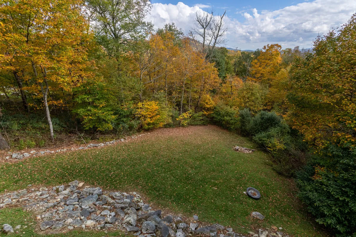 A wide outdoor area surrounded by autumn foliage and striking rock formations, with open grassy space ideal for picnicking and nature walks. The scene offers a taste of the activities available—hiking, bird watching, and relaxation in nature.