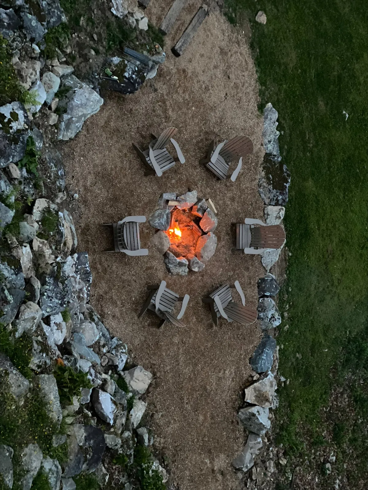 This image showcases a welcoming outdoor stone fire pit encircled by comfortable chairs, set against rugged rock formations. The arrangement invites guests to gather, share stories, and enjoy evenings under the stars, perfectly embodying the communal and cozy atmosphere described in the section.